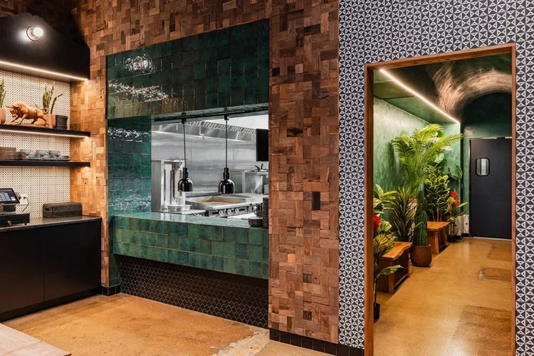 The open kitchen framed in green zellige tile and end-grain wood block walls